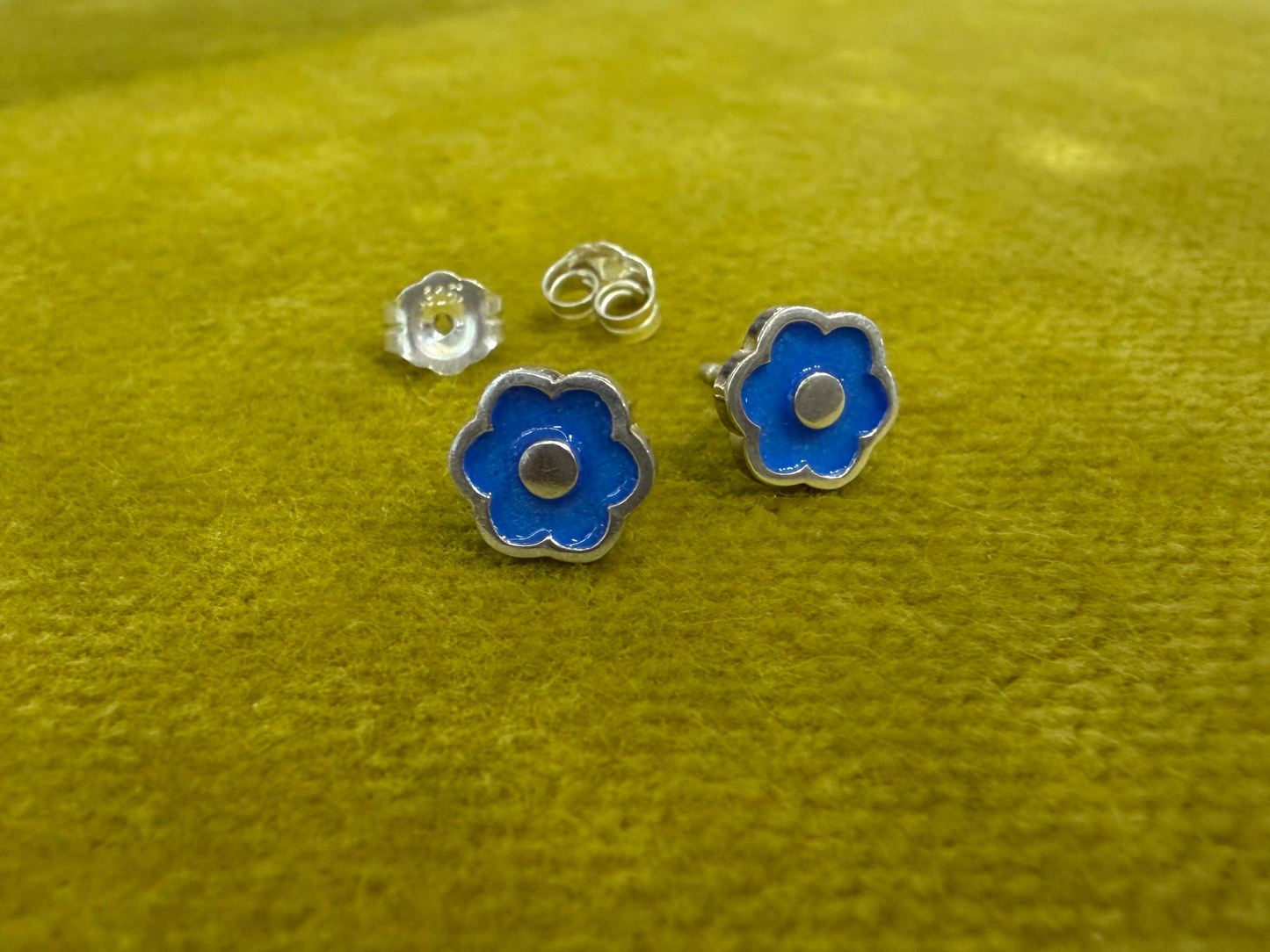 Small flower-shaped studs by Ellyse Bendillo, delicate silver earrings featuring intricate floral designs.