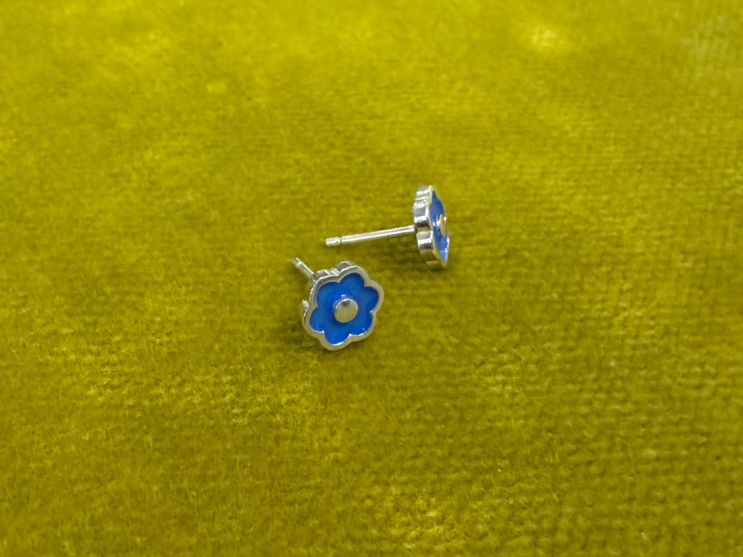 Small flower-shaped studs by Ellyse Bendillo, delicate floral jewelry with intricate petal details and silver finish.
