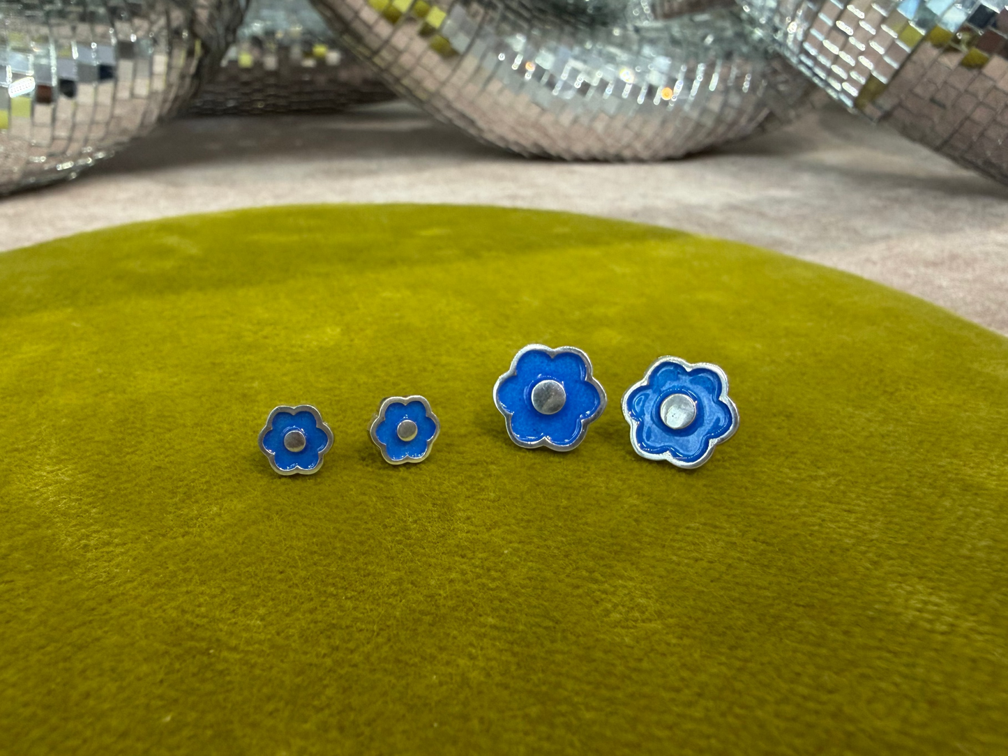 Small flower-shaped studs by Ellyse Bendillo featuring delicate floral designs in silver-tone metal.