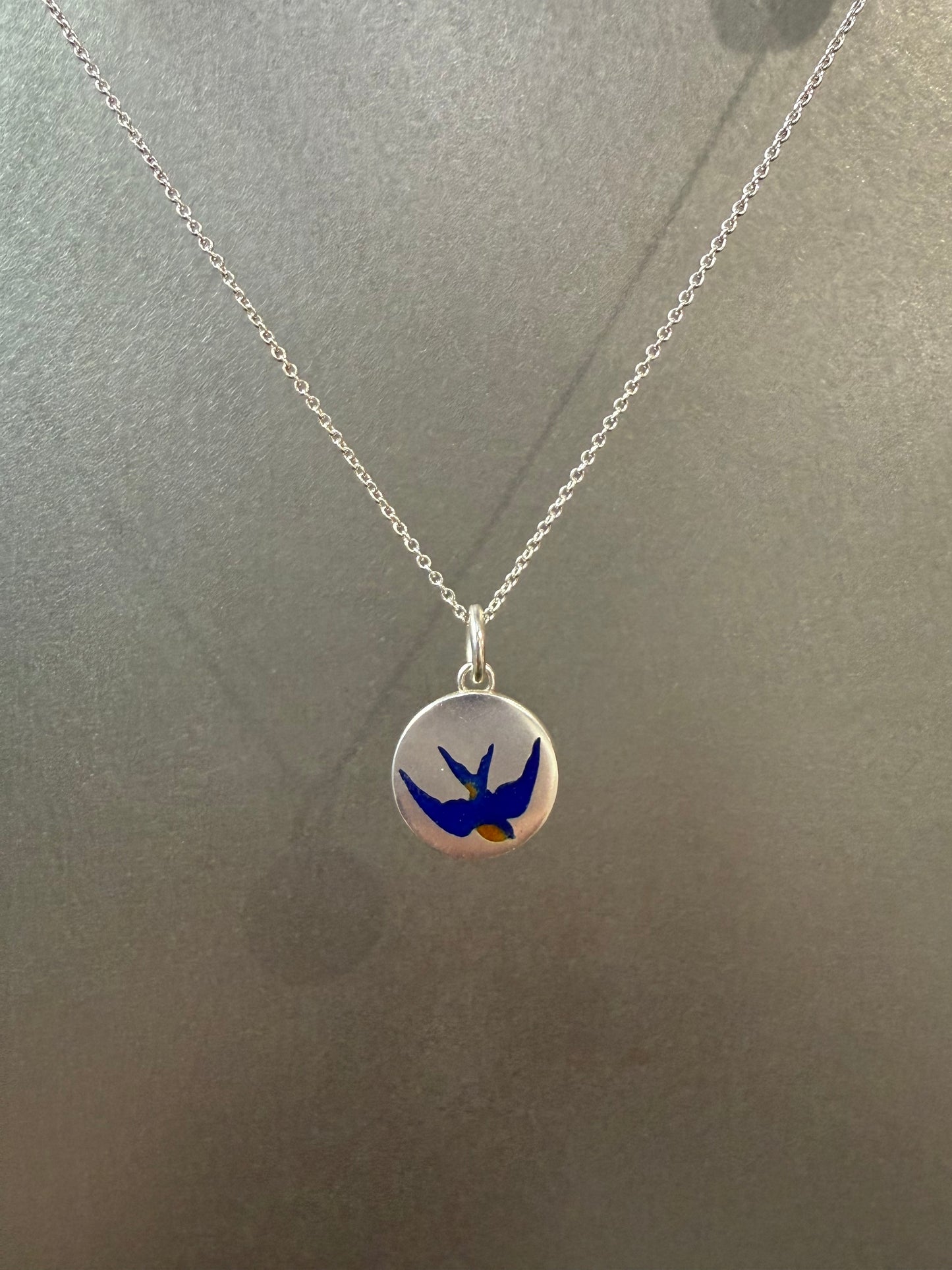 Ellyse Bendillo swallow charm, delicate silver jewelry piece with intricate bird design, close-up view of the charm's details