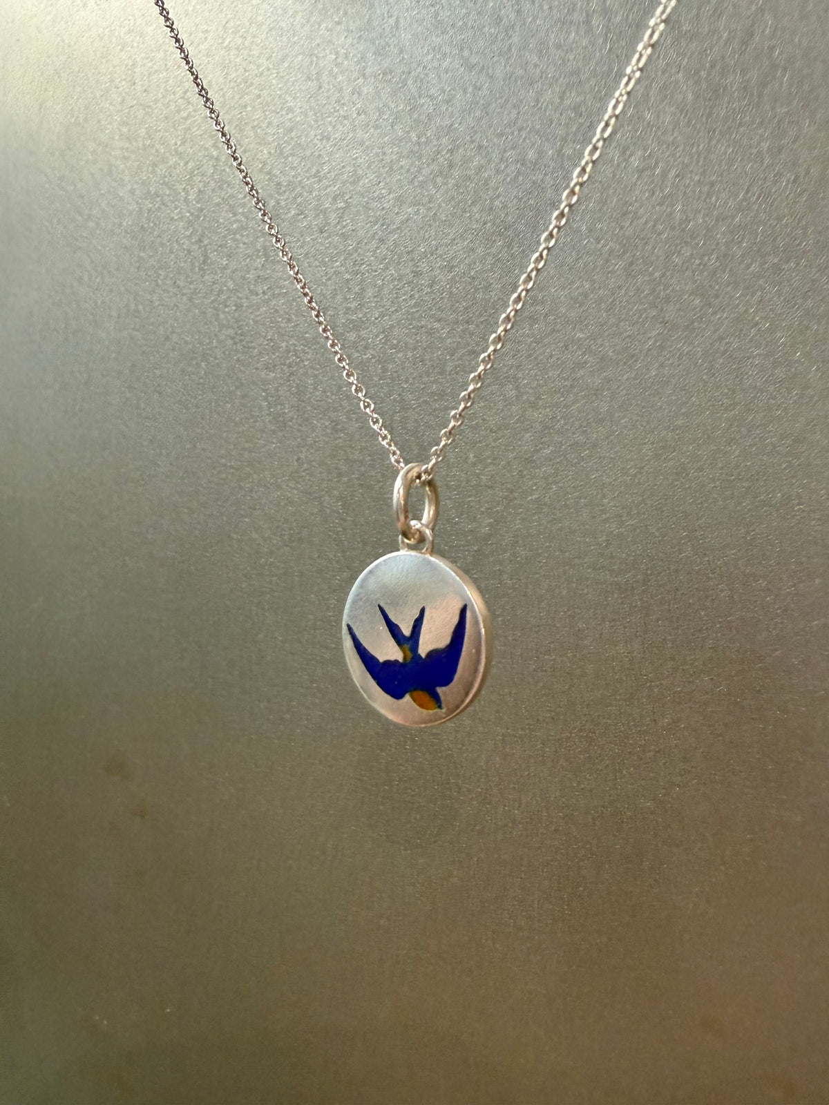 Ellyse Bendillo swallow charm, delicate silver jewelry charm with intricate bird design on a white background