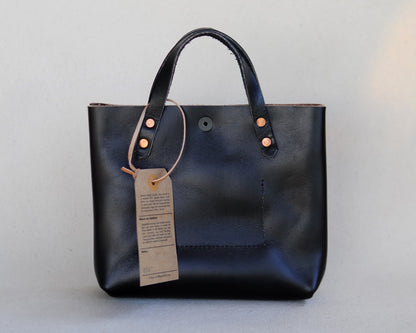 Black leather mini tote bag by Spartan Made, showing the back view with sleek design and sturdy handles.