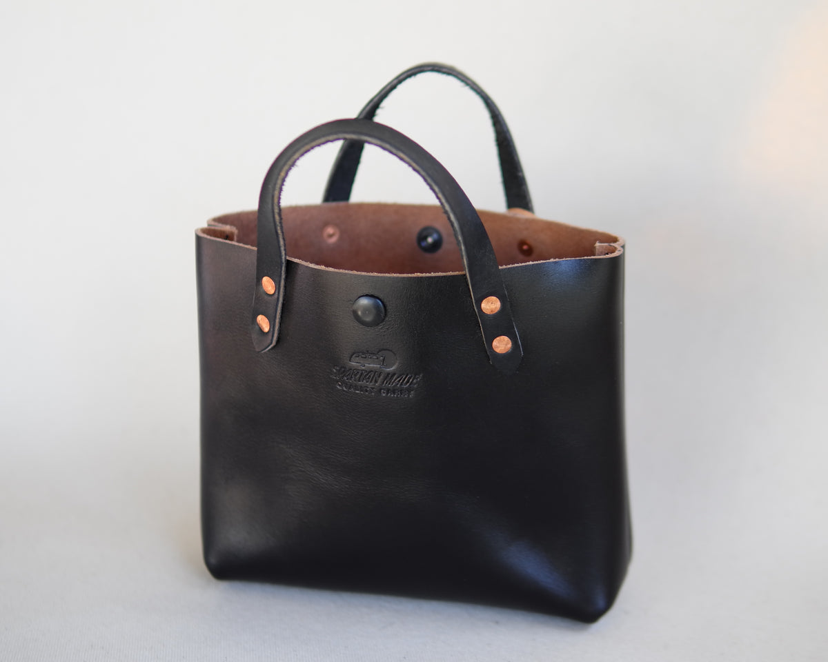 Black leather mini tote bag by Spartan Made, front view showing sleek design and structured shape.