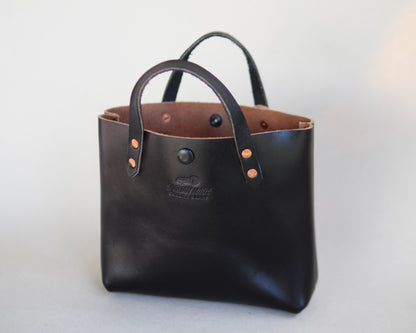 Black leather mini tote bag by Spartan Made, front view showing sleek design and structured shape.
