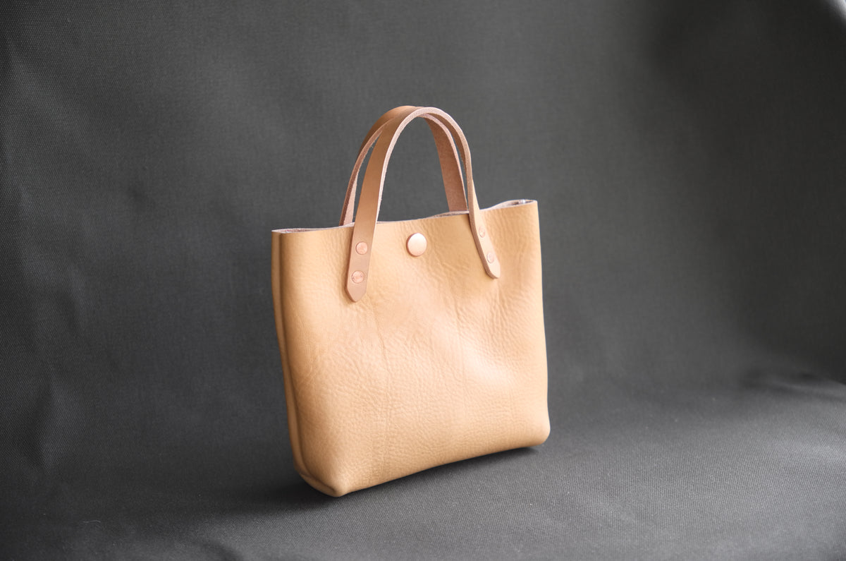 Natural leather mini tote bag by Spartan Made, front view showing compact design and sturdy handles.