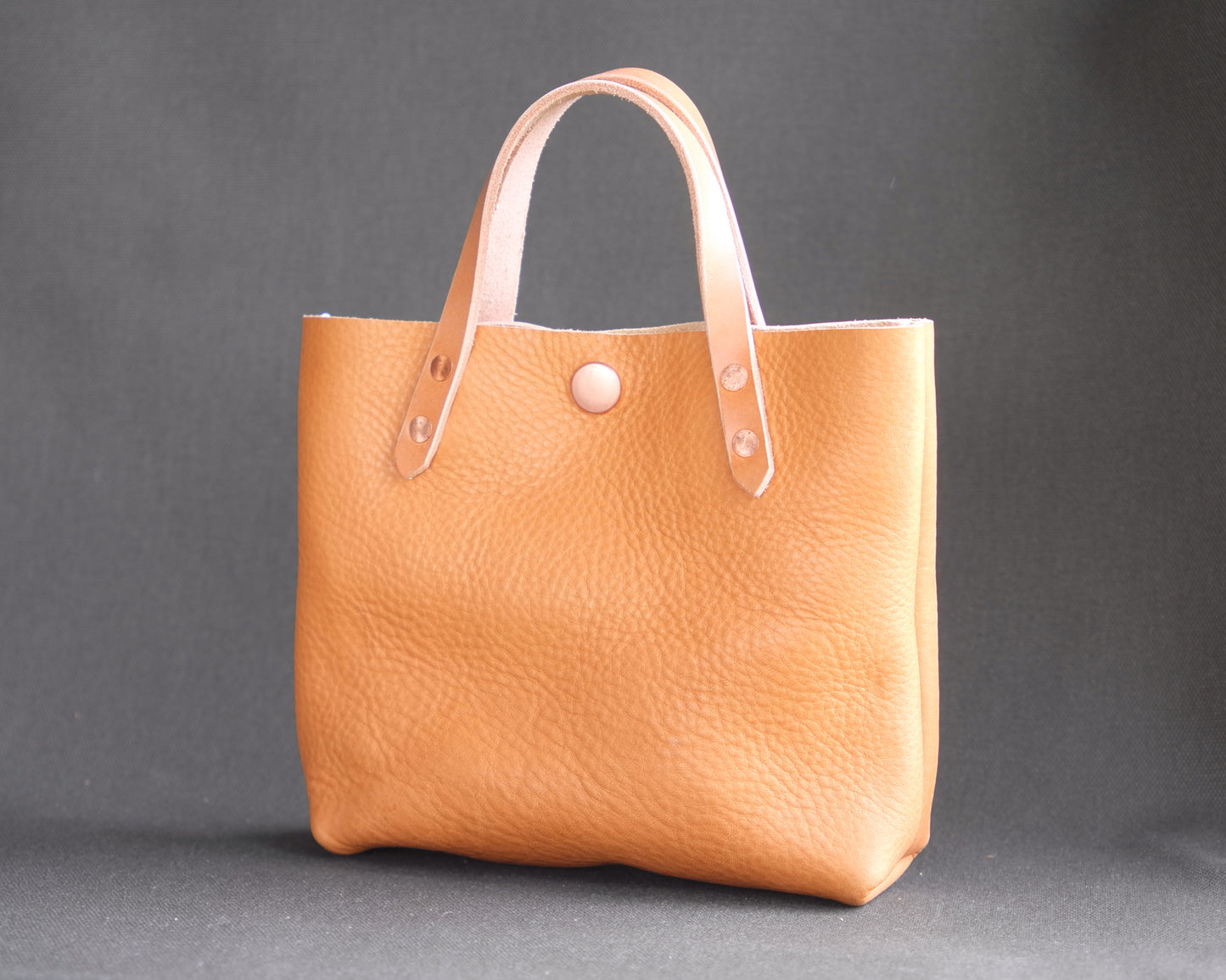 Natural leather mini tote bag from Spartan Made showing the front view with sleek design and sturdy handles.