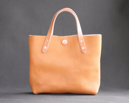 Spartan Made leather mini tote bag with natural finish, front view showcasing sleek design and compact size.