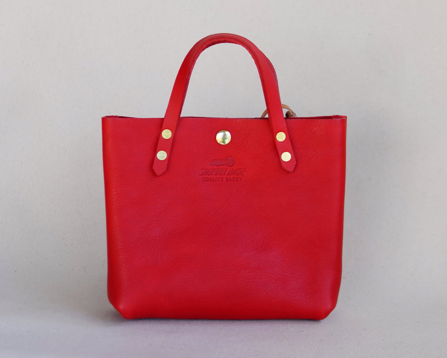 Red leather Spartan Made mini tote bag with sturdy handles and sleek design, perfect for everyday use.