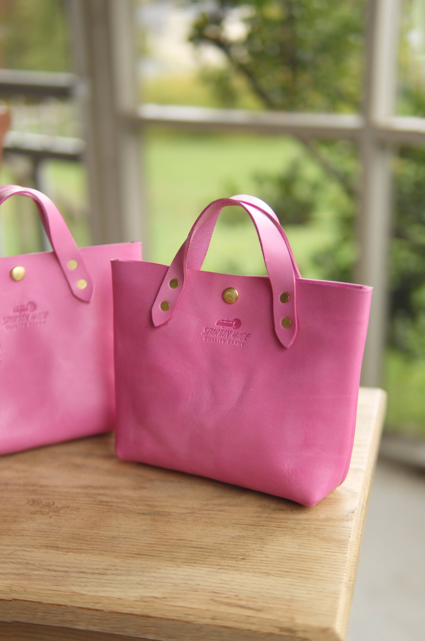 Pink leather mini tote bag from Spartan Made with two compartments and sturdy handles for versatile everyday use.