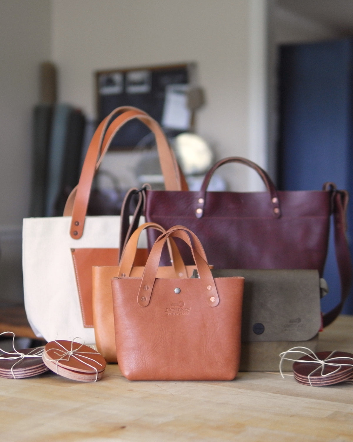 Group of medium-sized Spartan Made leather mini tote bags with sturdy handles and sleek design, displayed together.