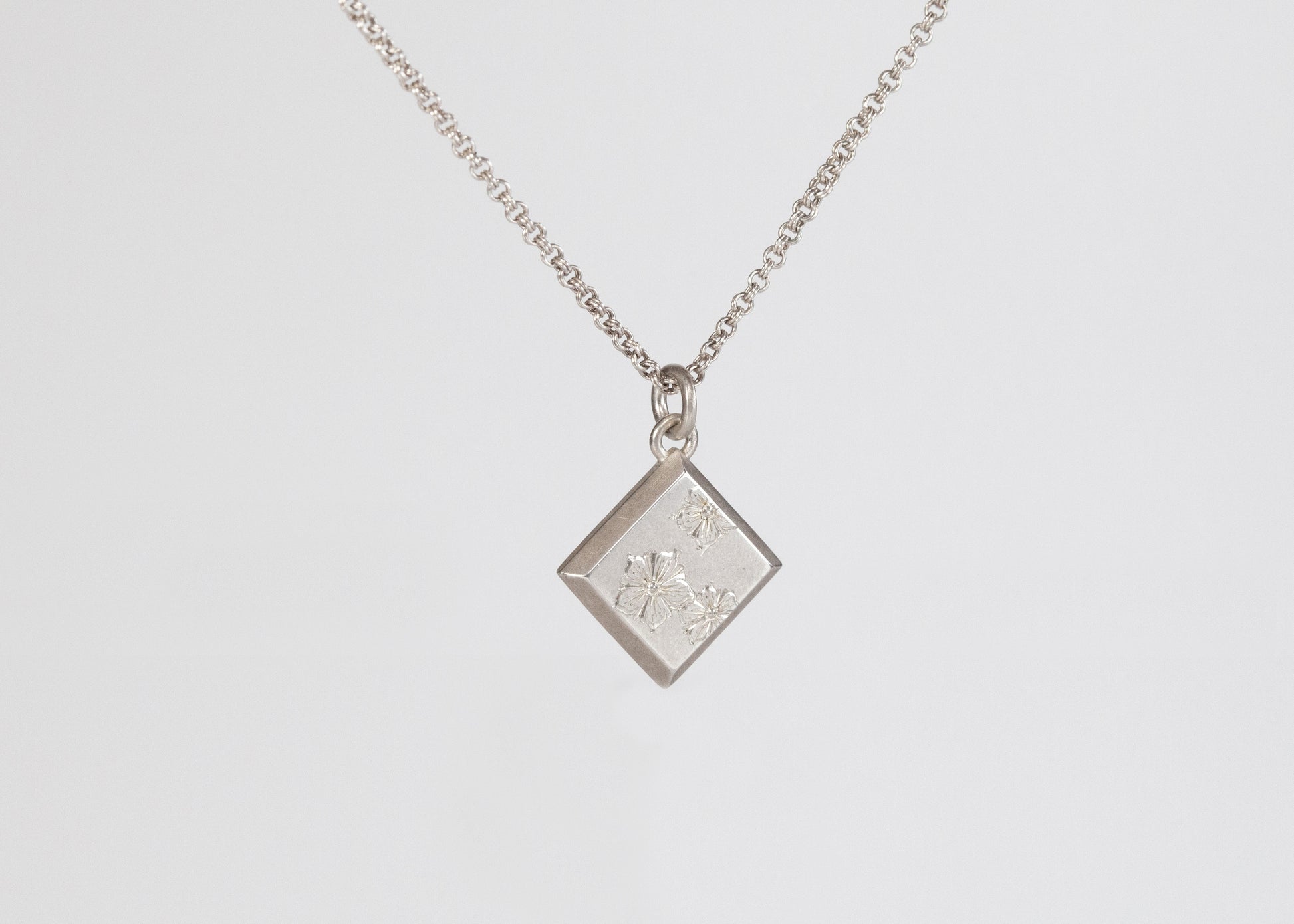 Silver wildflower pendant necklace by The Tiny Jeweler featuring a delicate floral design on a chain.