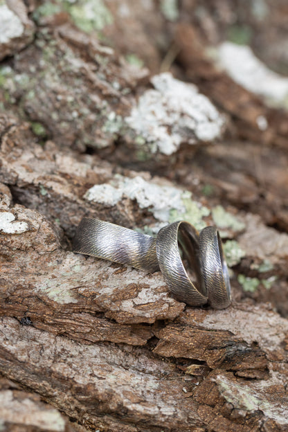 Textured band ring by The Tiny Jeweler, showcasing a close-up of the elegant, detailed design on a sleek metal band.