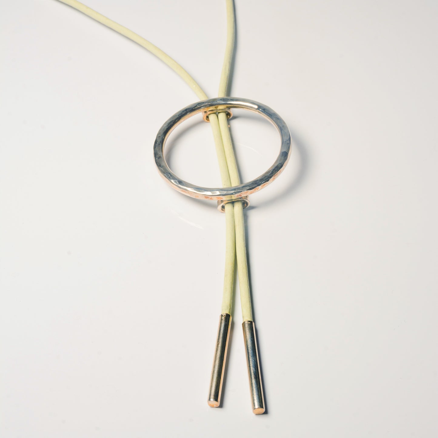 Silver bolo tie by Echo Metals featuring a sleek, polished design with a decorative slide and braided leather cord.