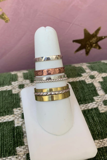 Set of Alloy Atelier stacking rings in various sizes and finishes, displayed on a neutral background.