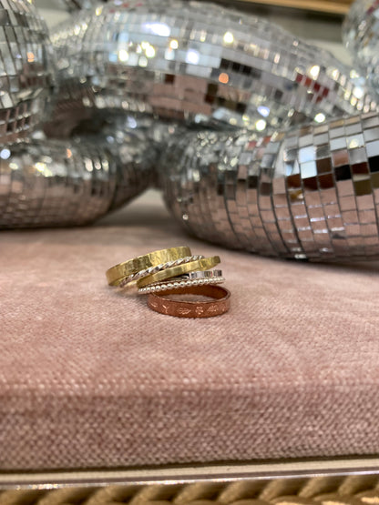 Stacking rings from Alloy Atelier displayed with sample rings on a dark background with a disco chain in the background.